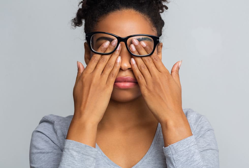 lady in glasses rubbing her eyes