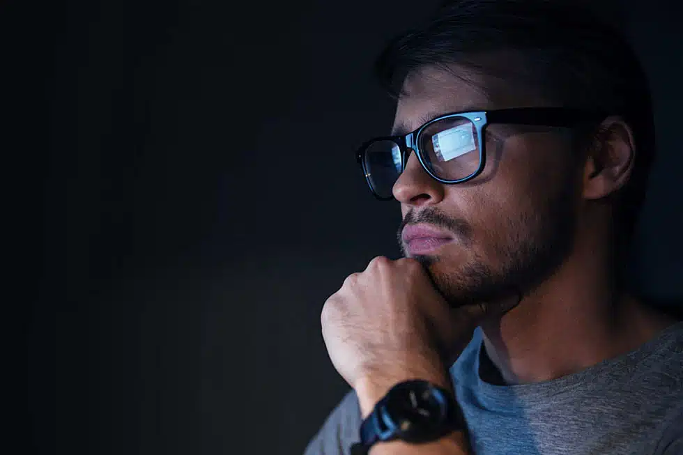 man wering blue light glasses to protect his eyes from constant screen time