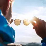 a man looking at his sunglasses lenses