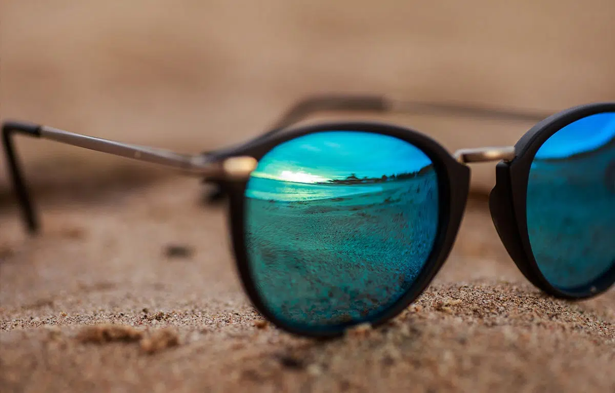 A pair of mirrored sunglasses on a sand