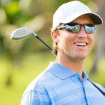 a man playing golf wearing a pair of sports glasses