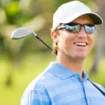 a man playing golf wearing a pair of sports glasses