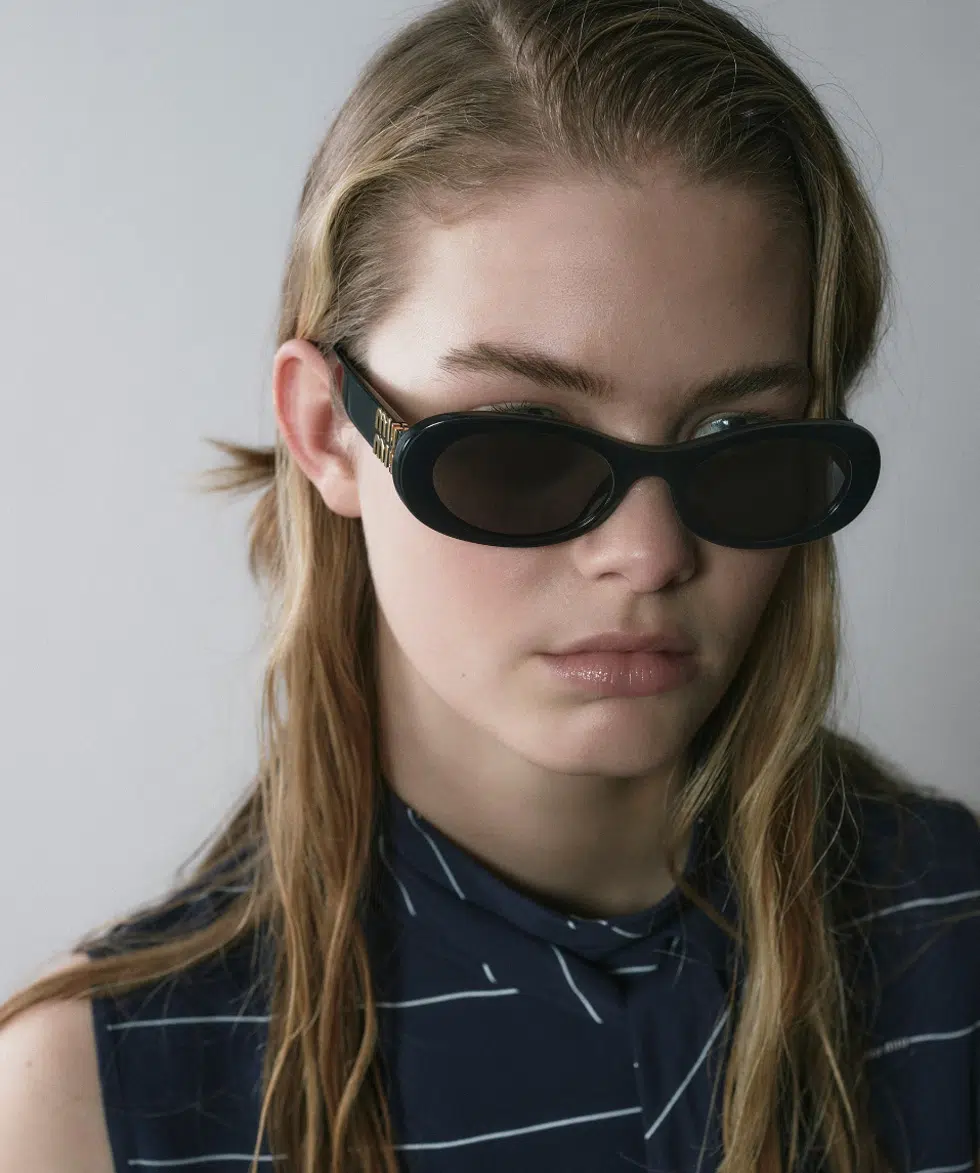 A person wearing a pair of Miu MIu sunglasses lenses