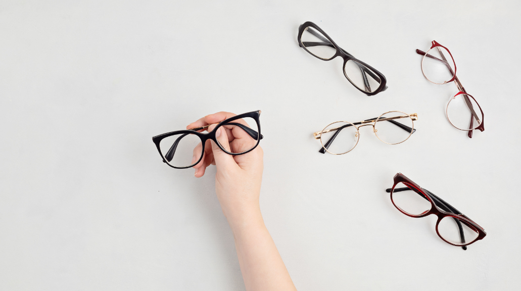 Flat lay of woman's hand holding glasses frame with other frames in view