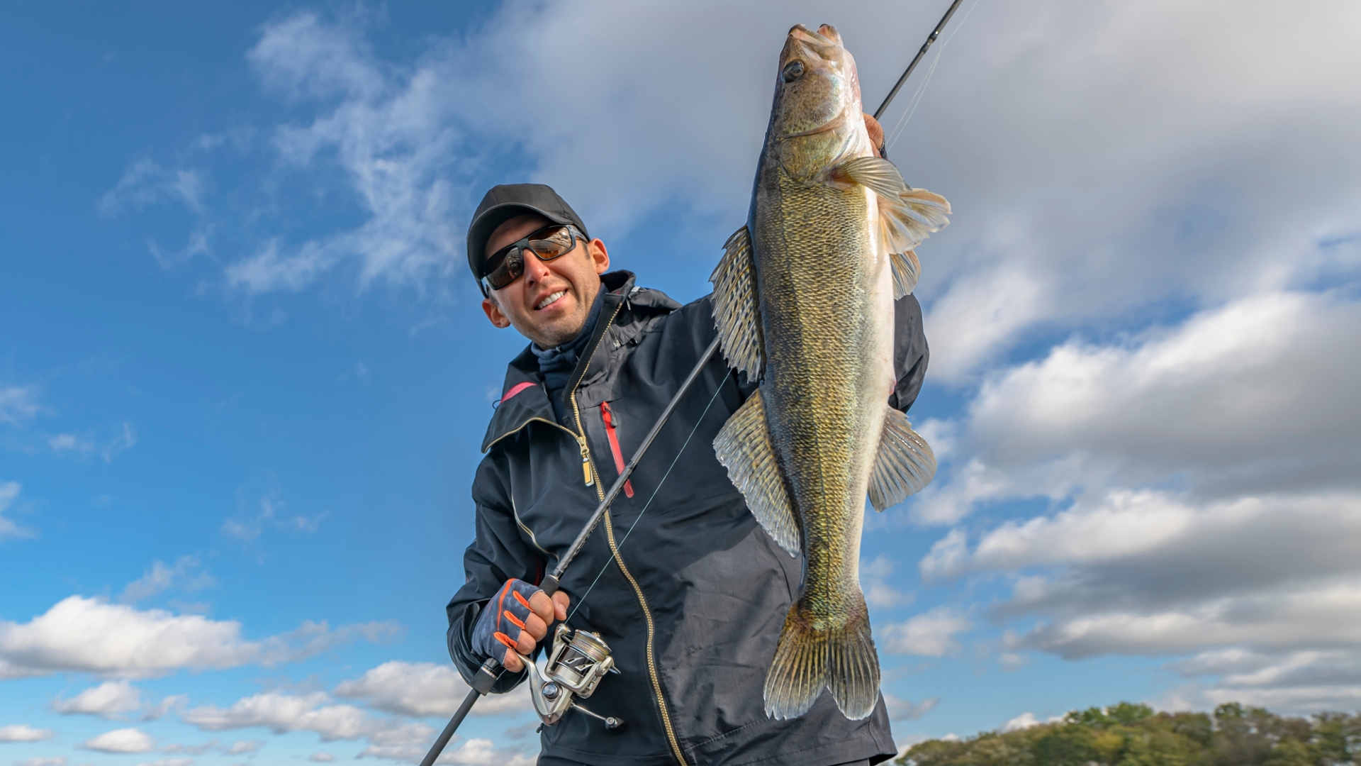 Man holding up fish in boat with glasses on