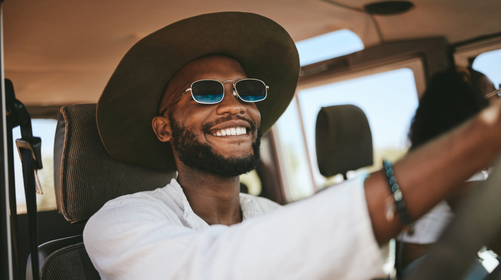 Happy man driving a caravan on a summer vacation, journey or adventure smiling wearing sunglasses