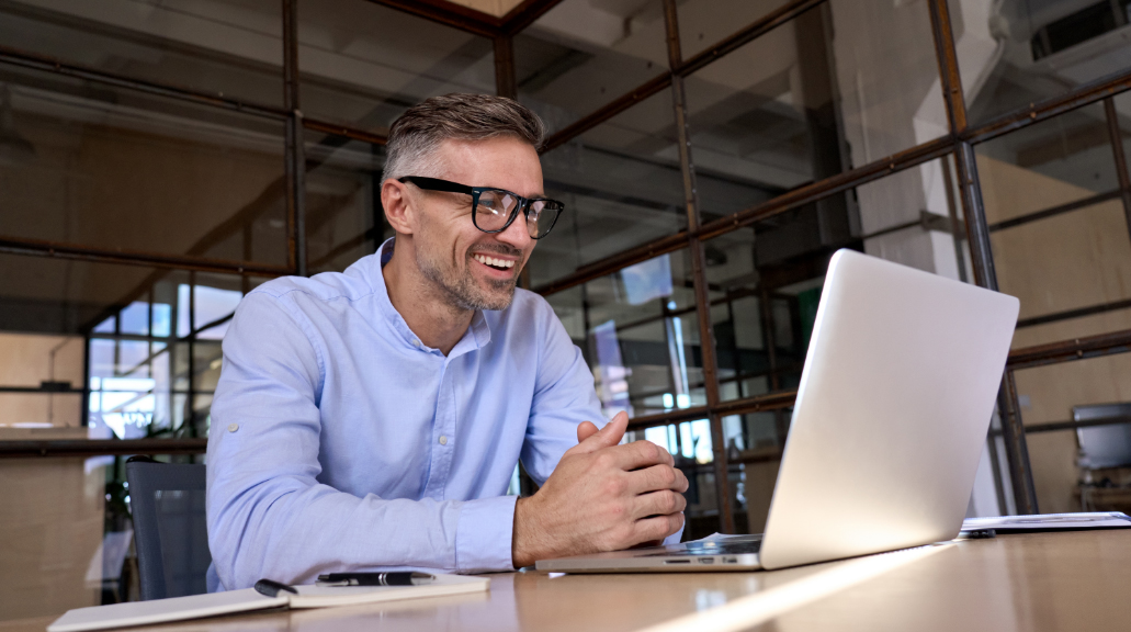 Happy business man wearing glasses looking at laptop computer