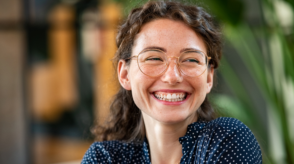 Portrait of laughing young woman wearing spectacles in office