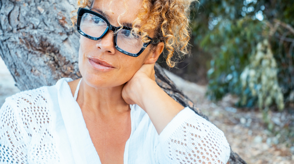 Portrait of woman outdoors wearing big black glasses looking away and smiling