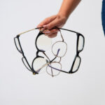 Person holding multiple pairs of glasses in a bright indoor setting