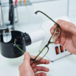 Male optician hands holding glasses with green frame