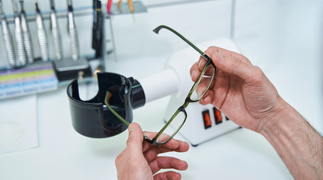 Male optician hands holding glasses with green frame
