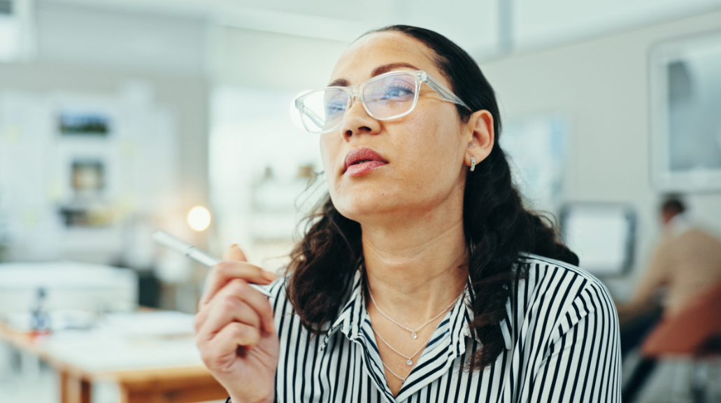 Business woman wearing glasses, holding pen thinking