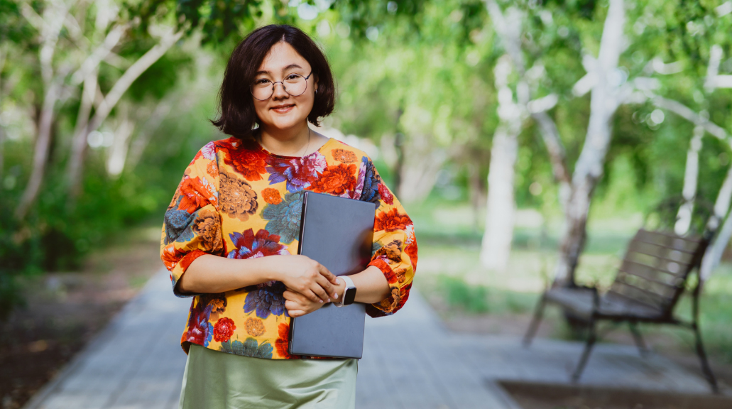 Confident young professional woman wearing glasses with laptop in summer city park