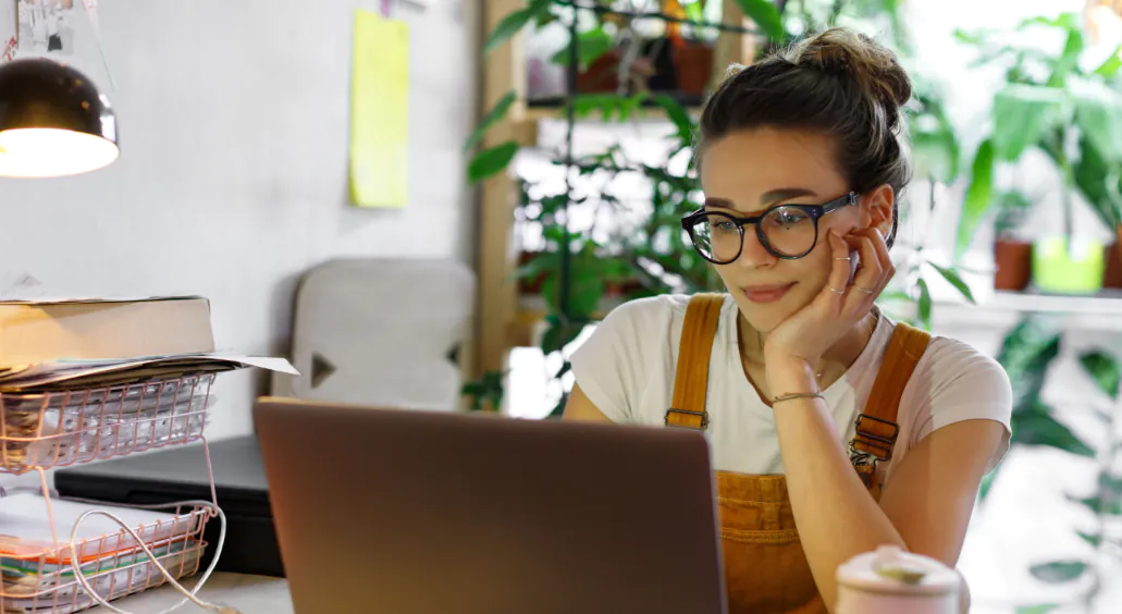 Young smiling female wearing glasses using laptop